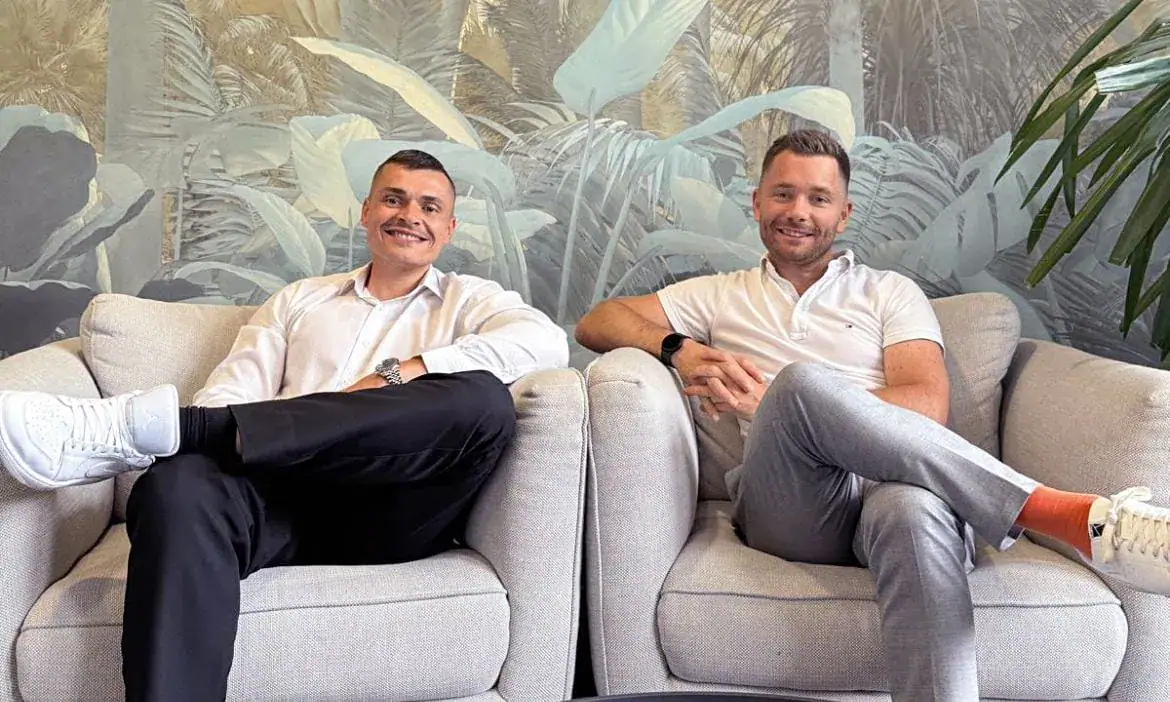 Freunde im modernen Wohnzimmer sitzend, entspannt und lächelnd, stilvolle Atmosphäre.