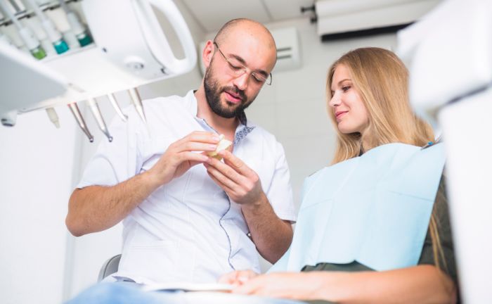 Mann untersucht Zahn eines Patienten in Dentalpraxis medizinisch.