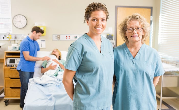 Zuversichtliche Krankenschwestern stehen gegen Paar mit Baby im Hintergrund