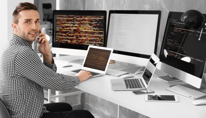 Junger Programmierer vor Computerbildschirmen