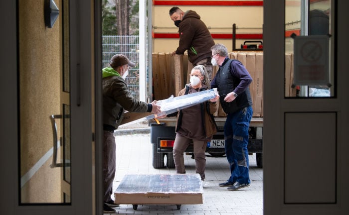 Freiwillige Helfer laden Betten aus einem LKW, um eine Unterkunft für Flüchtlinge einzurichten.