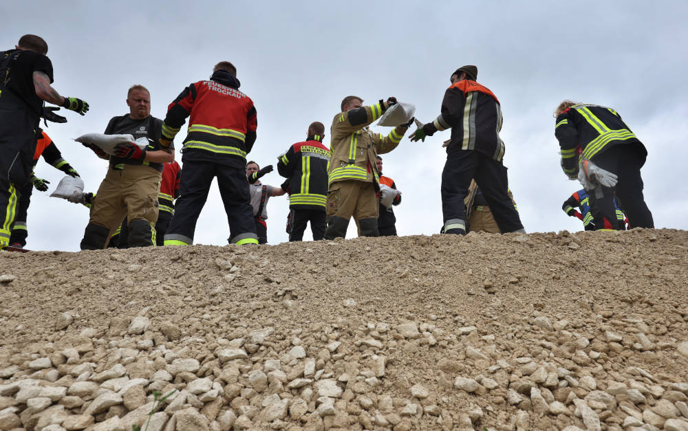 Feuerwehrleute und freiwillige Helfer im Ortsteil Auchsesheim nach einem Dammbruch