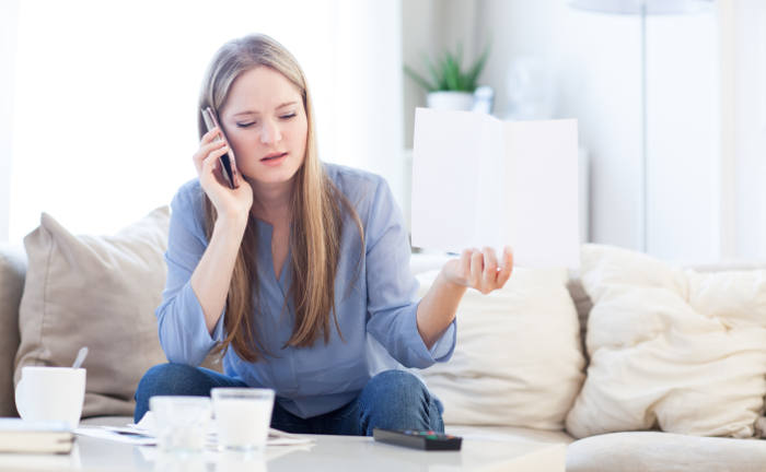 Junge Frau mit Brief in der Hand auf dem Sofa: Rechtschutzversicherer helfen Kunden bei Rechtsstreitigkeiten weiter