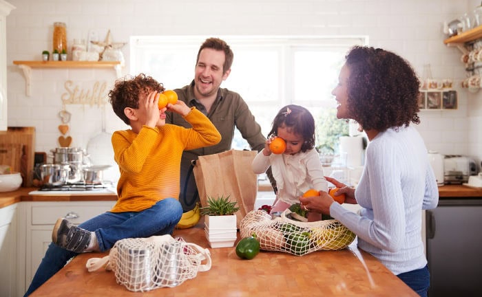 Junge Familie mit Gemüse-Einkauf in der Küche: Viele Verbraucher entscheiden sich nicht wegen nachhaltigen Produkten für Versicherer