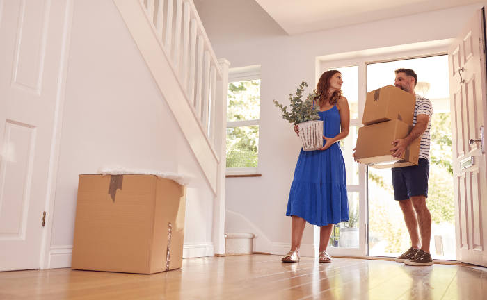 Junges Paar beim Einzug in ihr Haus: Eine eigener Immobilienkauf ist für viele Deutsche ein Traum, den sie sich gerne erfüllen möchten