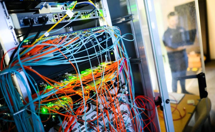 Serveransicht mit bunten Kabeln: Die IT von Firmen ist weltweit immer mehr vernetzt, das erhöht die Risiken für Cyberangriffe