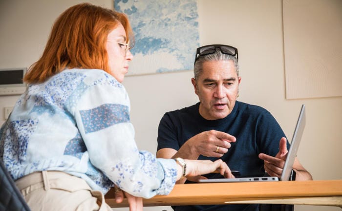 Junge Frau und älterer Mann sind über einen Laptop gebeugt: Jüngere Kunden sind für den Einsatz von KI in der Finanzberatung offener als Ältere