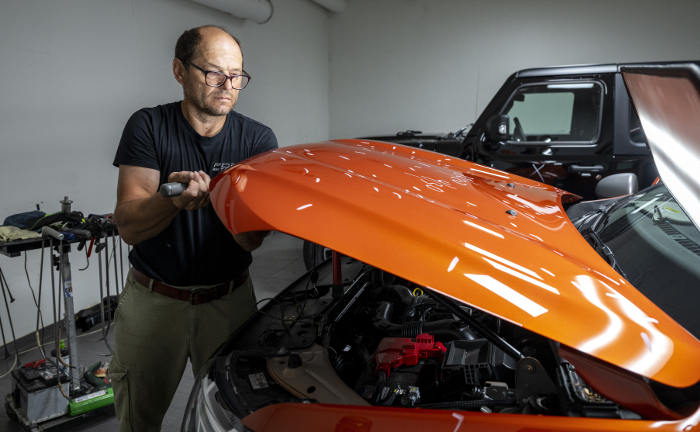 Petru Perju drückt mit einem Werkzeug Dellen aus einer Motorhaube: Hagelschäden sorgen für teure Reparaturen an Autos.