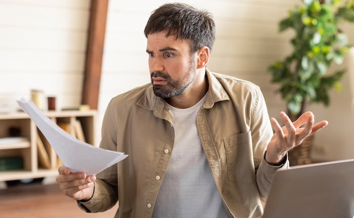 Überraschter Mann mit Rechnung: Die Zusatzbeitäge in der GKV steigen.