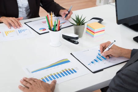 Zwei Männer analysieren Finanzdaten: Manche Akteure in den sozialen Medien versuchen die Kurse und Preise von Aktien zu beeinflussen. Foto: picture alliance / Panther Media | Andriy Popov