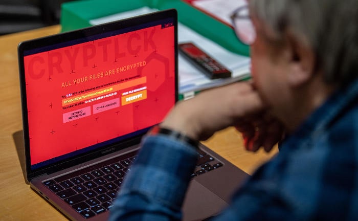 Mann sitzt vor Rechner mit verschlüsselten Daten durch ein Schadprogramm: Ransomware-Angriffe nehmen aktuell zu.