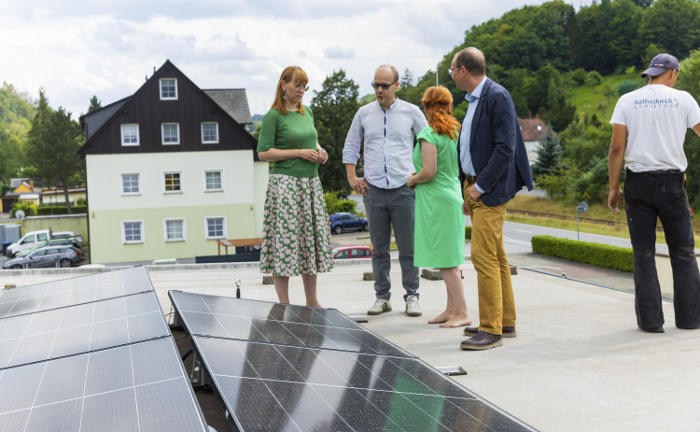 Sachsens Demokratie- und Gleichstellungsministerin Katja Meier; Sachsens Energie- und Klimaschutzminister, Wolfram Günther, und Franziska Schubert, Fraktionsvorsitzende von Bündnis 90/Die Grünen im Sächsischen Landtag (v.l.), schauen sich die Photovoltaikanlage auf dem Dach der Firma Nomos Glashütte an.