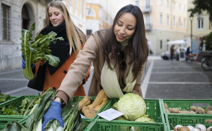 Zwei Frauen kaufen auf einem Wochenmarkt ein: Nicht alle Personen können sich nachhaltige Produkte leisten.