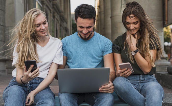 Junge Leute sitzen zusammen vor einem Laptop: Junge Anleger haben oftmals weniger Scheu vor Aktien-Investments als ältere.