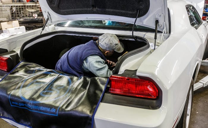 Ein Automechaniker repariert den Kofferraum eines Autos: Die Kosten für KFZ-Ersatzteile sind in den vergangenen Jahren stark gestiegen.