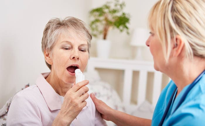 Pflegerin hilft einer Patientin mit einem Inhalator: Coronamaßnahmen und Boni für Pfleger haben Krankenkasse Milliarden gekostet.