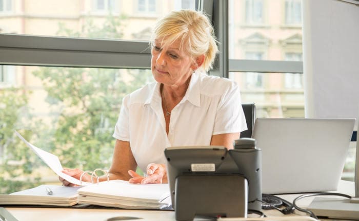 Eine Rentnerin arbeitet in einem Büro: Deutsche Rentner arbeiten aus unterschiedlichen Gründen trotz Ruhestand weiter.