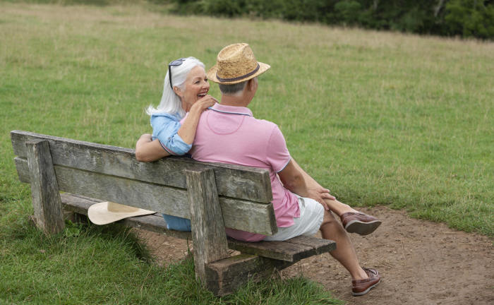 Rentnerpaar sitzt entspannt auf Parkbank: Eine aktuelle Studie kam zu dem Ergebnis, dass eine lebenslange Rente besser für einen entspannten Ruhestand ist als ein Auszahlplan.