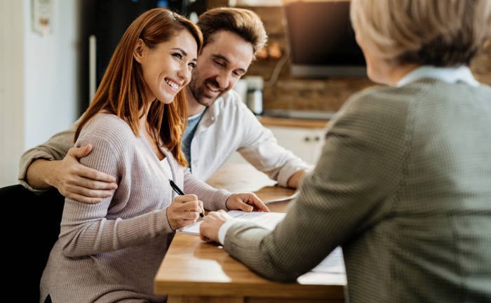 Junges Paar unterschreibt einen Versicherungsvertrag bei Maklerin: Die Ratingagentur Ascore hat die drei besten Versicherungstarife 2024 bestimmt.