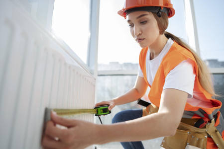 Handwerkerin misst einen Heizkörper: Die Kosten für eine energetische Sanierung können Steuerzahler teils von der Steuer absetzen. Foto: Freepik