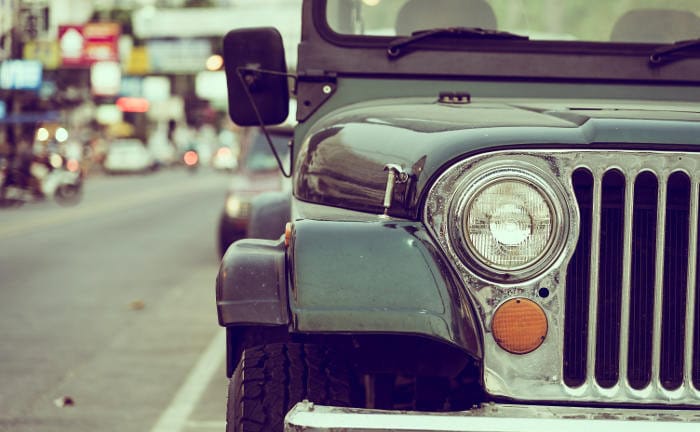 Ausschnitt eines alten Autos auf der Straße: Viele Autofahrer versuchen für ihre immer älteren Fahrzeuge bei deren Autoversicherung zu sparen.