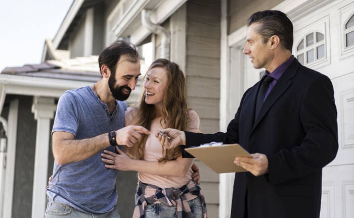 Ein junges Paar bekommt vom Makler die Hausschlüssel: Interessenten für eine Wohnimmobilie machen aktuell Abstriche bei der Größe von Wohnungen und Häusern.