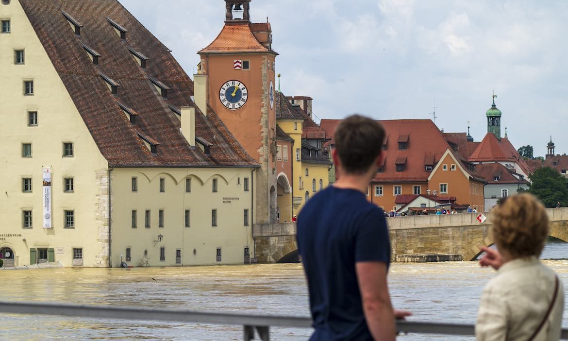 Passanten schauen am 6. Juni 2024 auf die überflutete Regensburger Altstadt: Wetterextreme wie das Hochwasser im Juni kamen die Versicherer auch 2024 wieder teuer zu stehen.