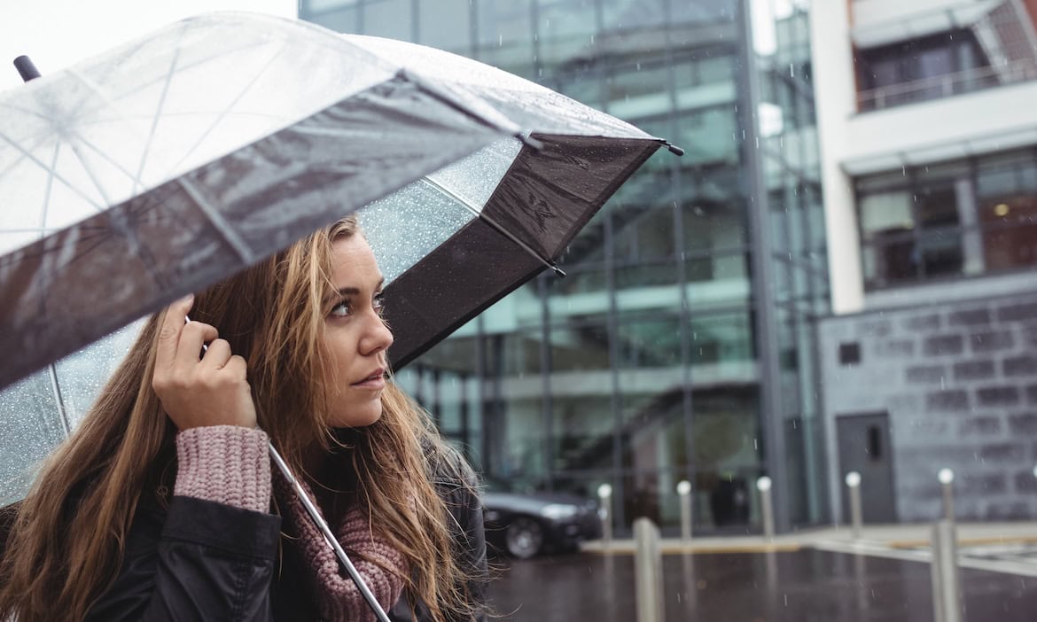 Frau steht mit Regenschirm im Regen: Wie Versicherer ihren Versicherungsvertrieb auch in Verlustsparten wie der Wohngebäudeversicherung auf Vordermann bringen können, erklären die Experten von Simon Kucher.