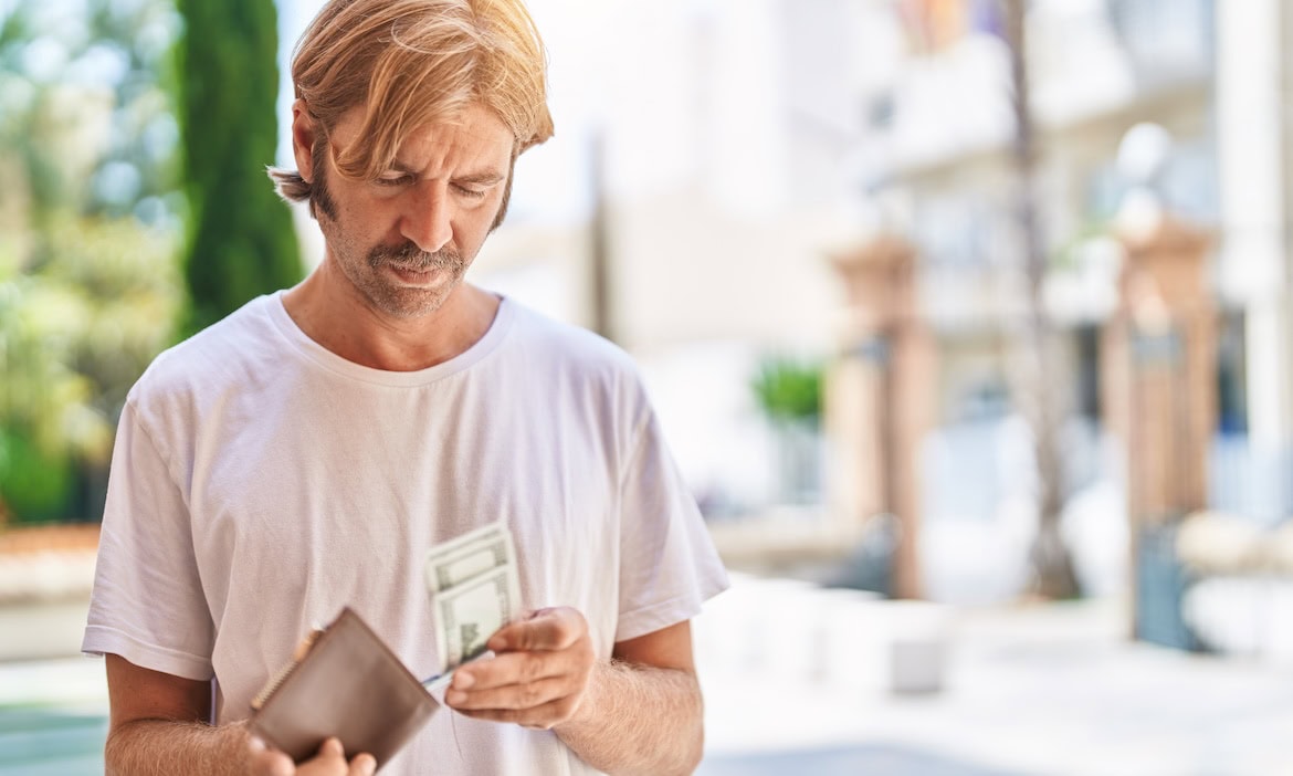 Mann zählt Geld auf der Straße: Die Armutsquote in Deutschland steigt weiter an.