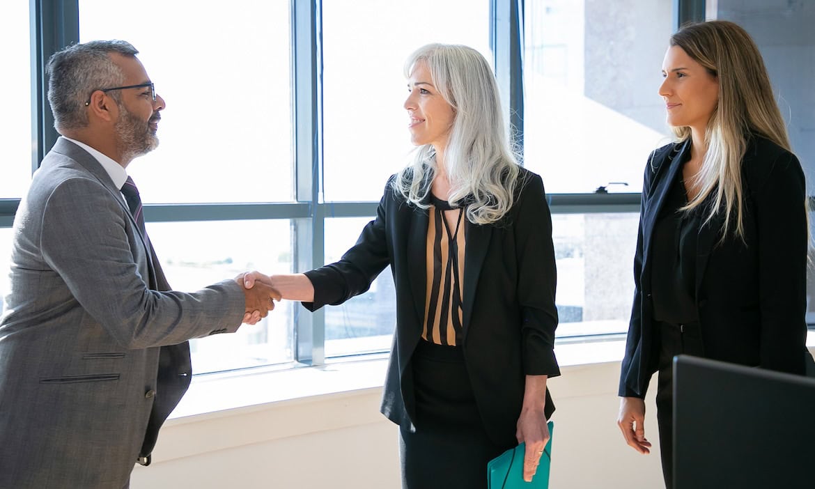 Manager und zwei Managerinnen geben sich die Hand: In den vergangenen Jahren kam es zu einigen Fusionen auf dem deutschen Markt für Versicherungen.