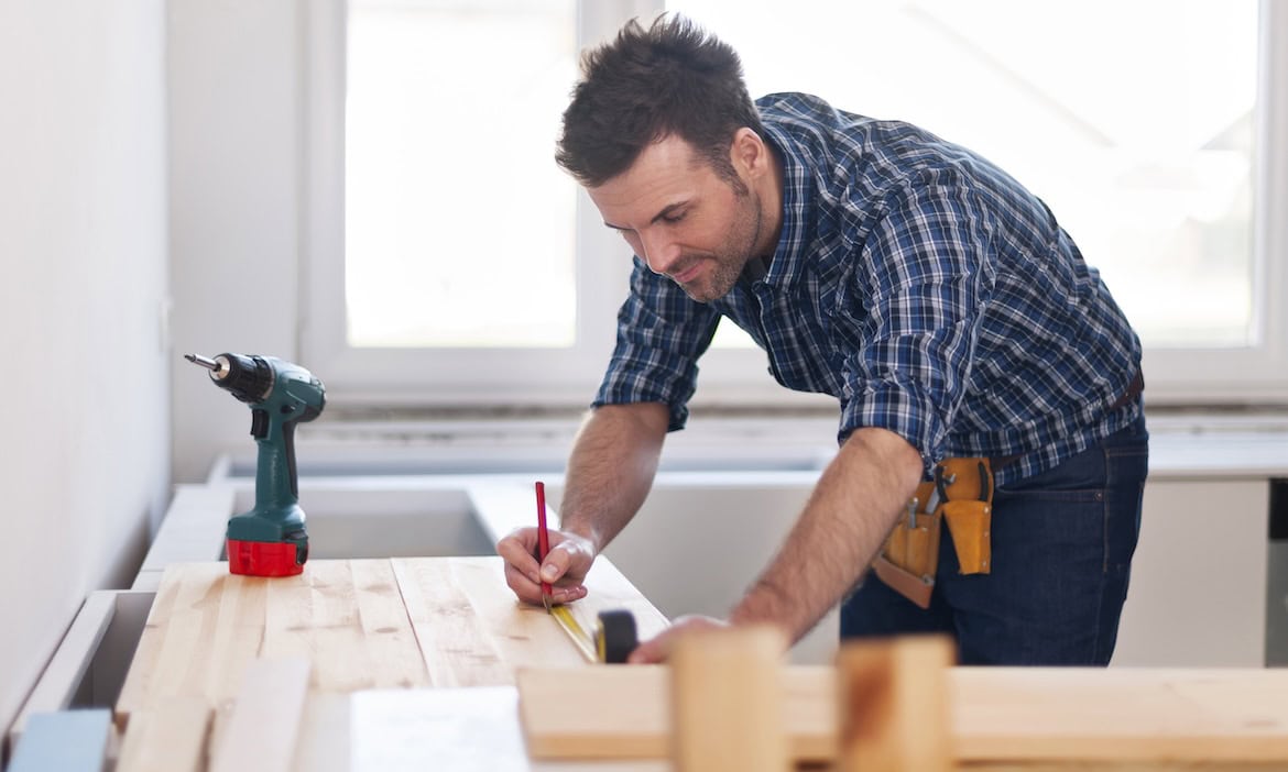 Handwerker misst Holzlatten: Handwerker zahlen hohe Prämien, wenn sie eine BU-Versicherung abschließen.