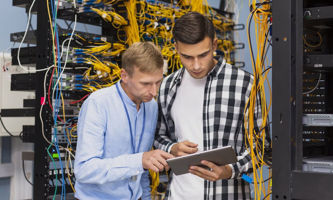 Zwei Mitarbeiter kontrollieren das IT-System: Ransomware-Angriffe auf mittelständische Firmen nehmen zu.