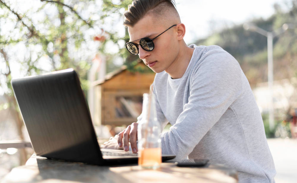 Junger Mann mit Laptop: Auf welchem Weg vergleicht er Versicherungen?