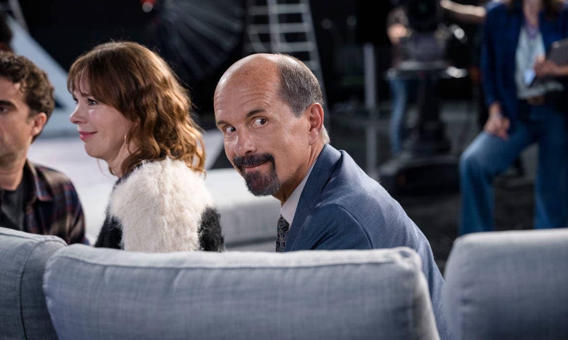 Besprechung bei Filmdreh in moderner Atmosphäre, selbstbewusster Mann im Fokus.