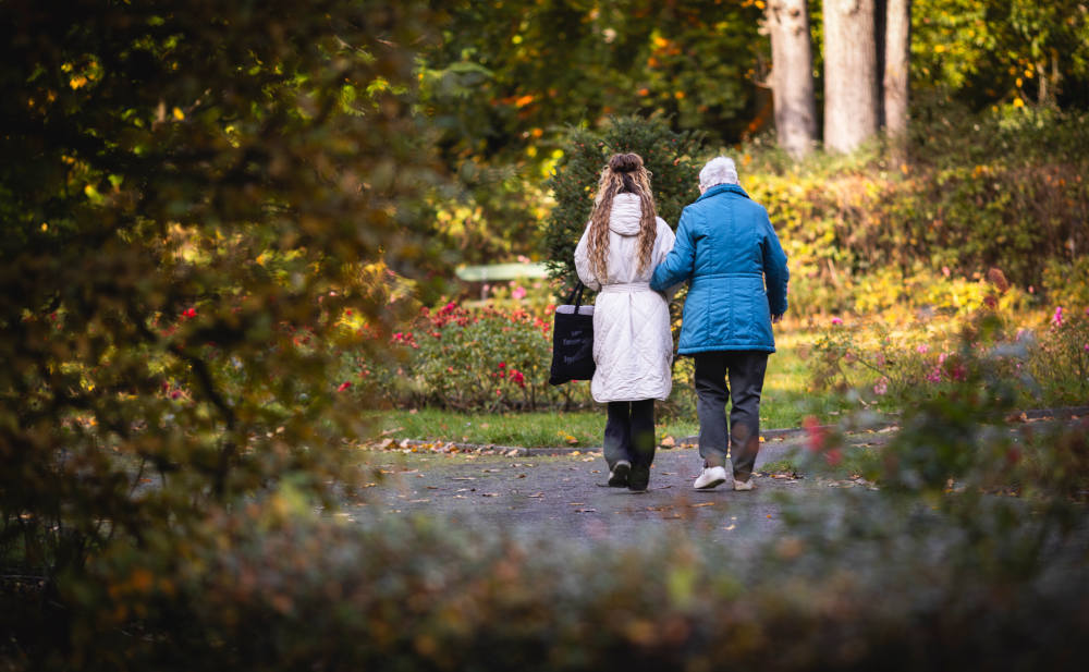 Freundliche ältere Frau und junge Frau beim Spaziergang im Park im Herbst.
