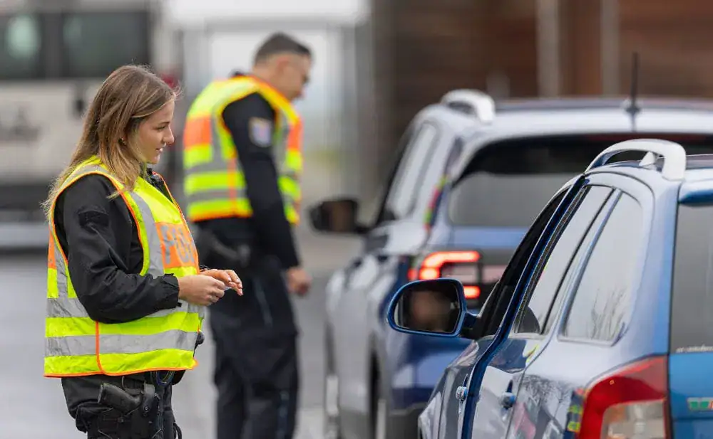Blaulichter Einsatz bei Verkehrskontrolle, Beamte kontrollieren Fahrzeuge auf der Straße.