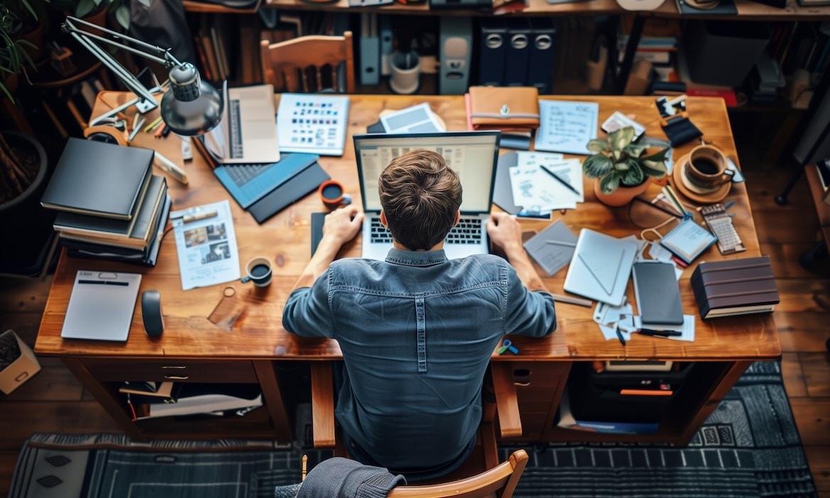 Detailliertes Bild einesArbeitsplatzes mit Laptop, Büromaterialien und Pflanzen für Finanz- und Versicherungsberatung.