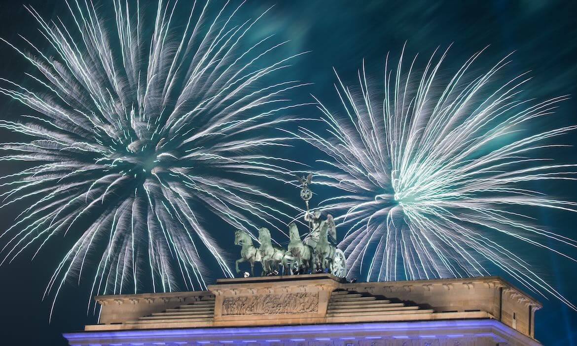 Farbfoto von Feuerwerk über der Berliner Pferdekutsche auf dem Brandenburger Tor bei Nacht, festliche Stimmung, Silvesterfeier.