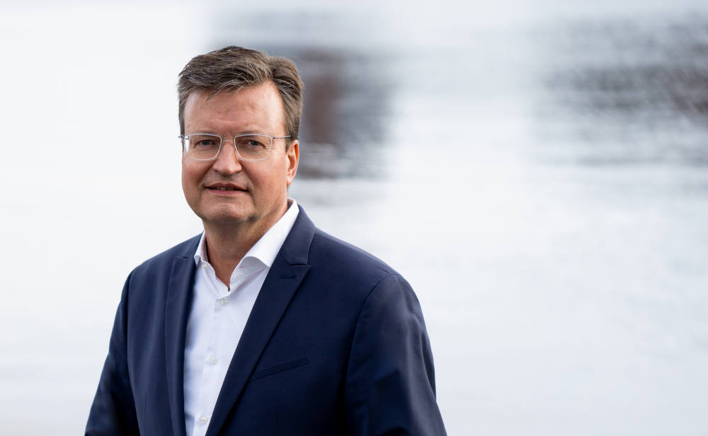 Erfahrener Geschäftsmann vor Wasser, professionelle Business-Porträtaufnahme.