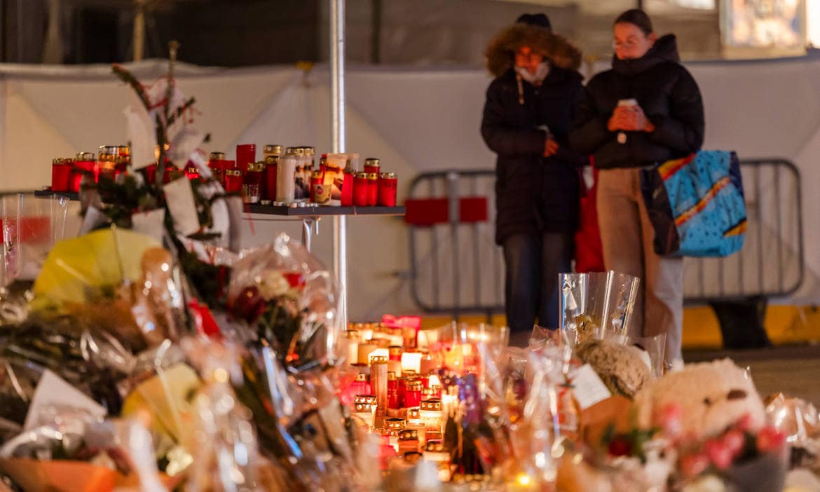 Abendliche Kerzen- und Blumenfahne am Gedenkenort bei einer Trauerfeier in der Dunkelheit.