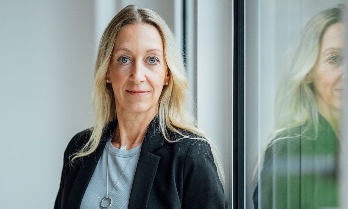 Modernes Porträt einer Frau im beruflichen Umfeld, symbolisiert Kompetenz und Vertrauen.