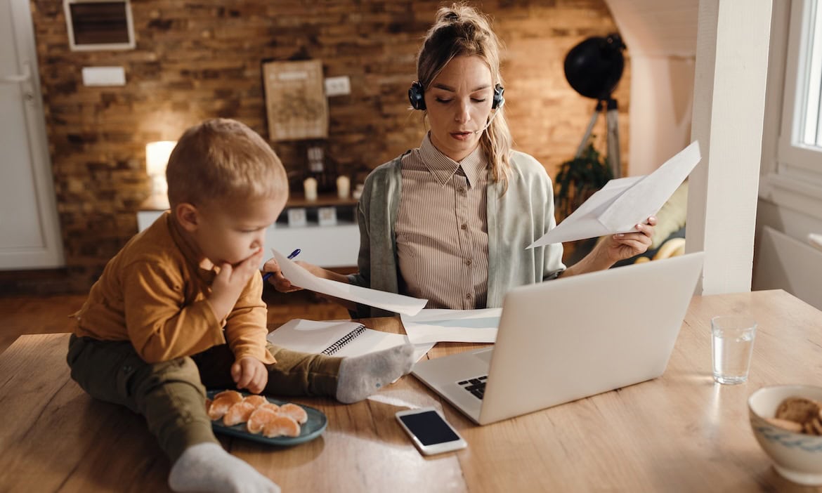 Papierarbeiten und Kinderbetreuung im Home Office, multitasking mit Laptop und Kind zu Hause.