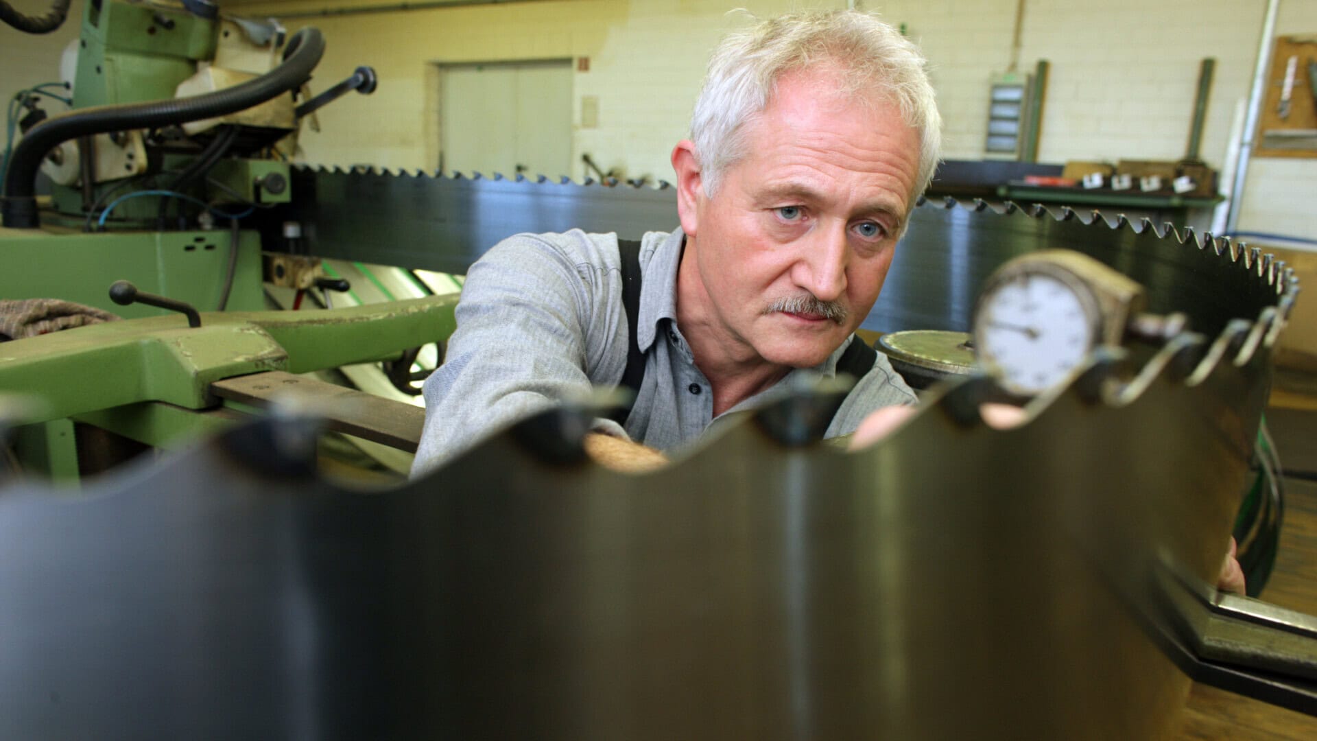 Älterer Mann überprüft eine große Maschine in der Werkstatt.