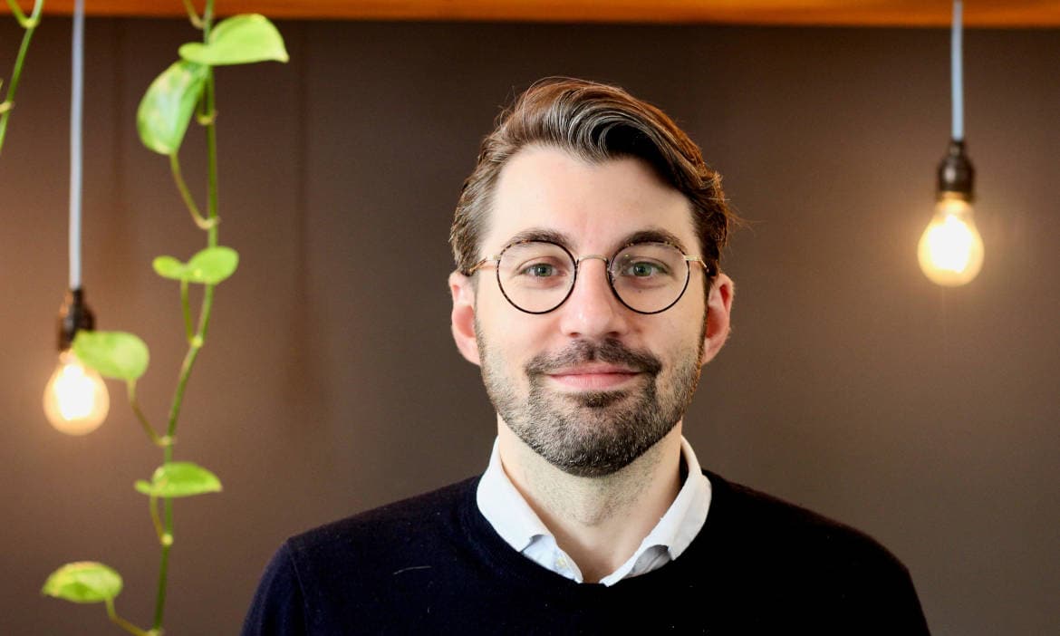 Hochwertiges Porträt eines Mannes mit Brille vor moderner Hintergrundbeleuchtung.