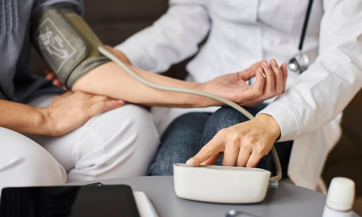 Arzt misst Blutdruck bei Patient im Sprechzimmer.