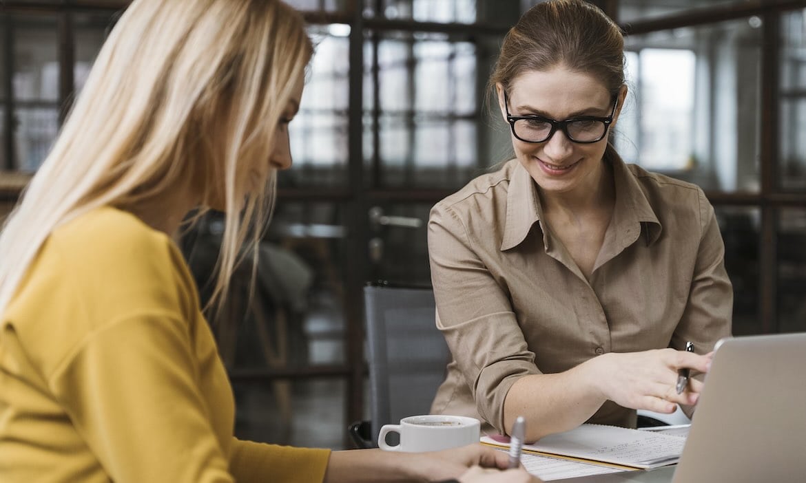 Zwei Frauen bei professioneller Versicherungsberatung im Büro, lächelnd und im Gespräch.