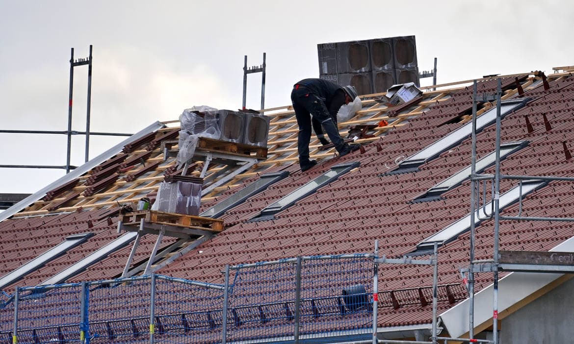Dachdecker installiert Solarmodule auf einem neugebauten Hausdach.