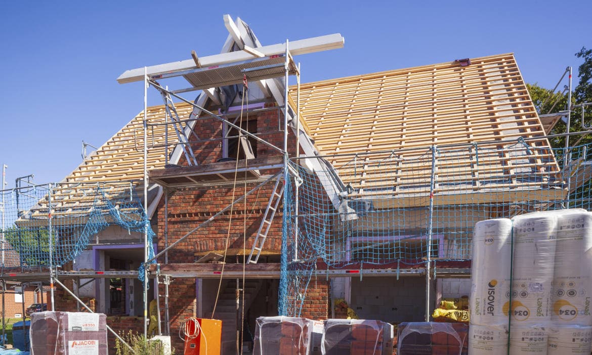 Neubau eines Hauses mit sichtbarer Dachkonstruktion und Gerüst.