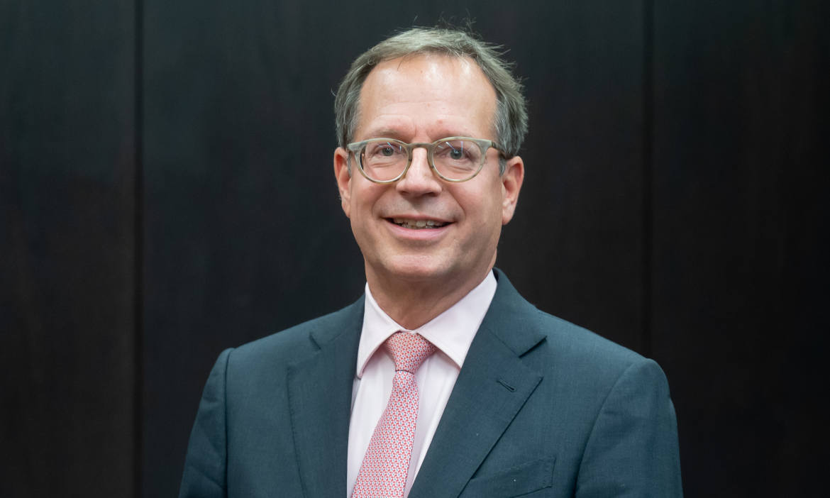 Mann in Anzug lächelt, symbolisiert Stabilität in der Versicherungsbranche.