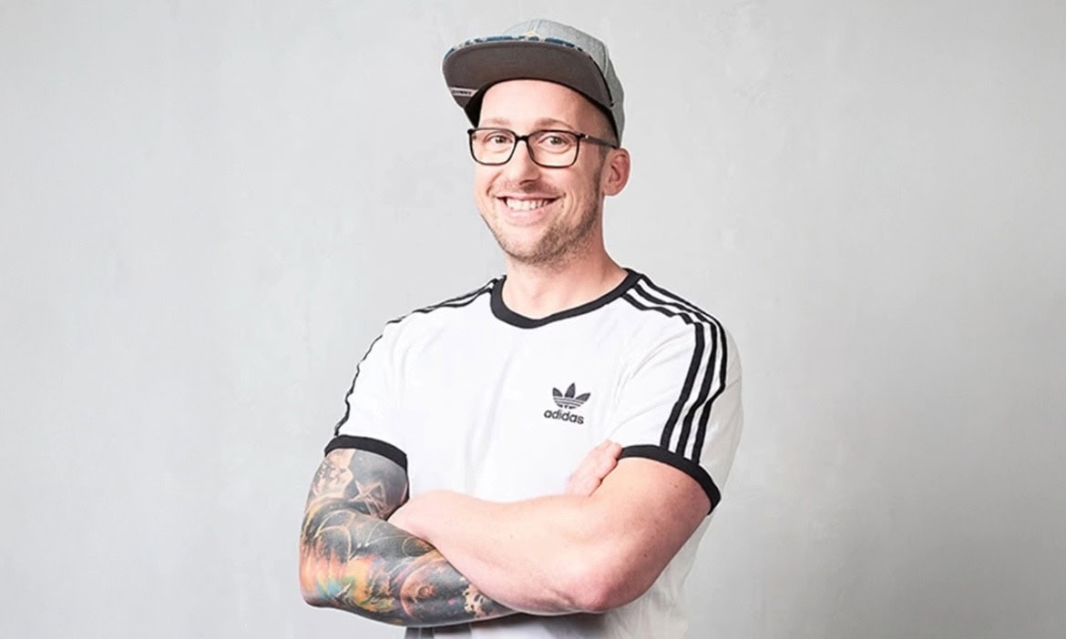 Berater mit Brille, Cap und tätowierten Armen, die Vertrauen und Kompetenz ausstrahlen.